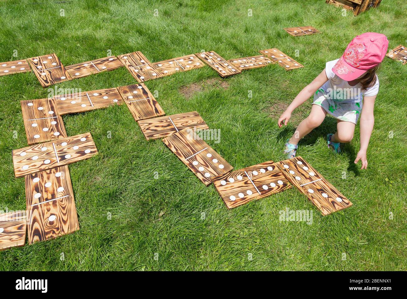 Girl playing in a large wooden dominoes laid out on the lawn. Games