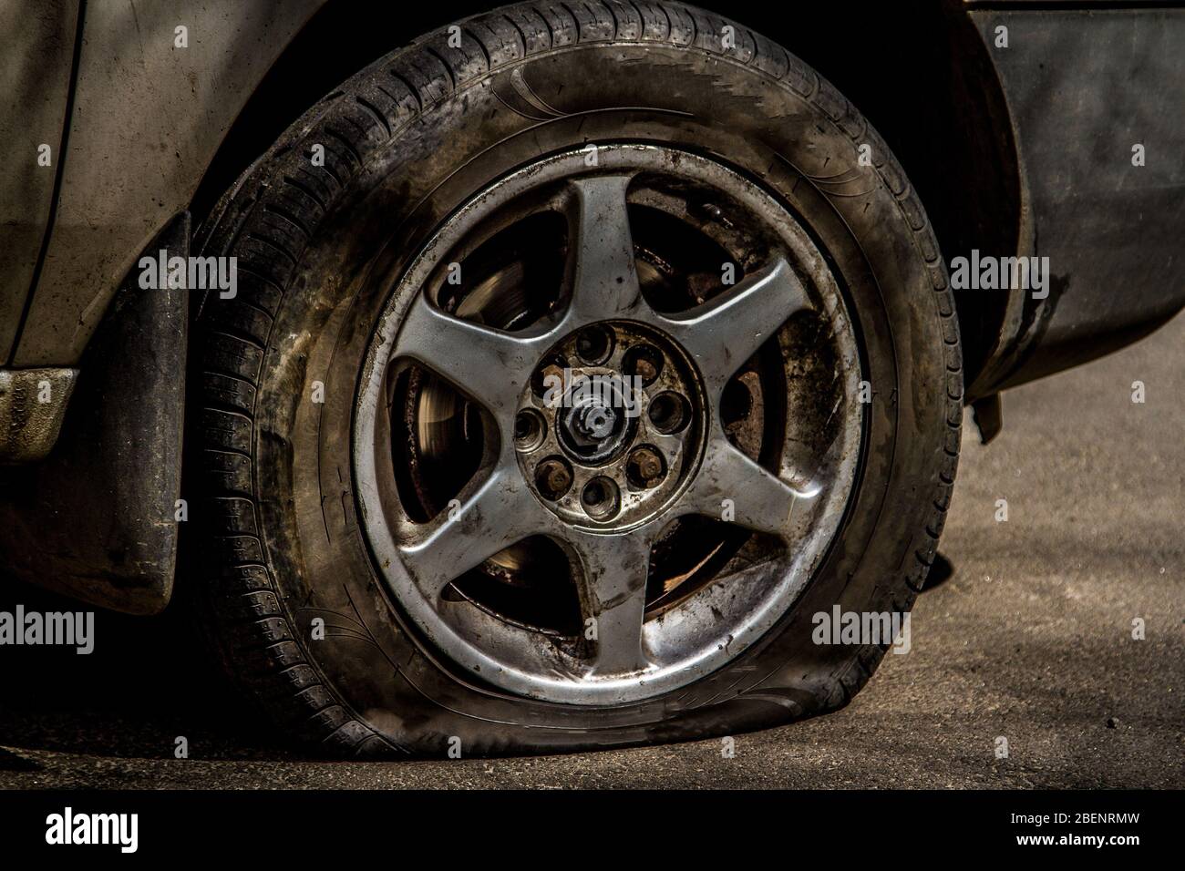The flat tire on the cast of the car drive. The deflated wheel of the car is close-up. Accident on the road. Stock Photo