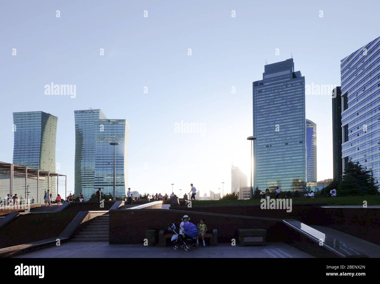 NUR-SULTAN, ASTANA, KAZAKHSTAN - JUNE 3, 2015: Fascinating city view at sunset time with sun shadows, reflections and silhouettse around. People are Stock Photo