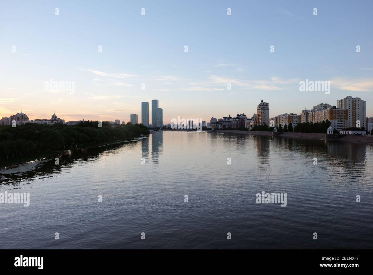 NUR-SULTAN, ASTANA, KAZAKHSTAN - JUNE 3, 2015: A beautifula panorama of Ishim river with smooth surface of water and evening city view Stock Photo