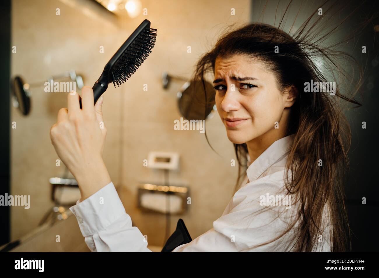 Woman doing her hair styling with a brush at home.Bad hair day.Daily