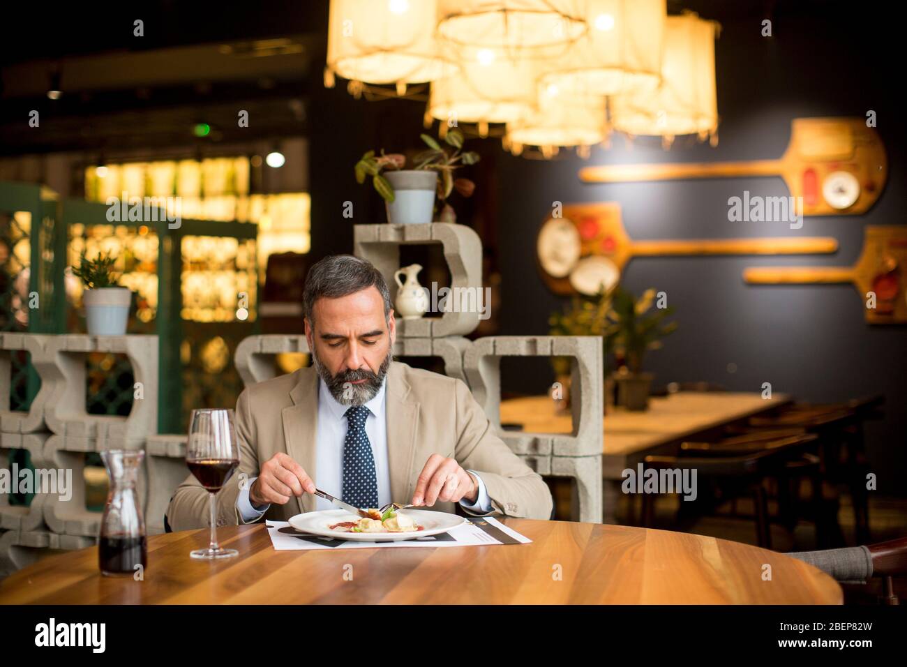 Handsome mature man drinking red wine during lunch in the restaurant