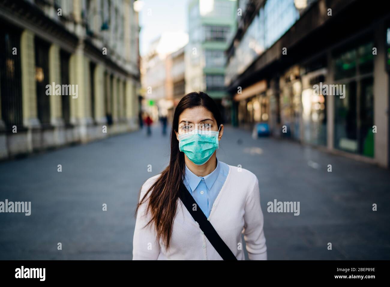 Suspicious young adult affected by the COVID-19.Walking,going to work during pandemic.Protective measures,mask wearing.Respecting guidelines.Empty str Stock Photo