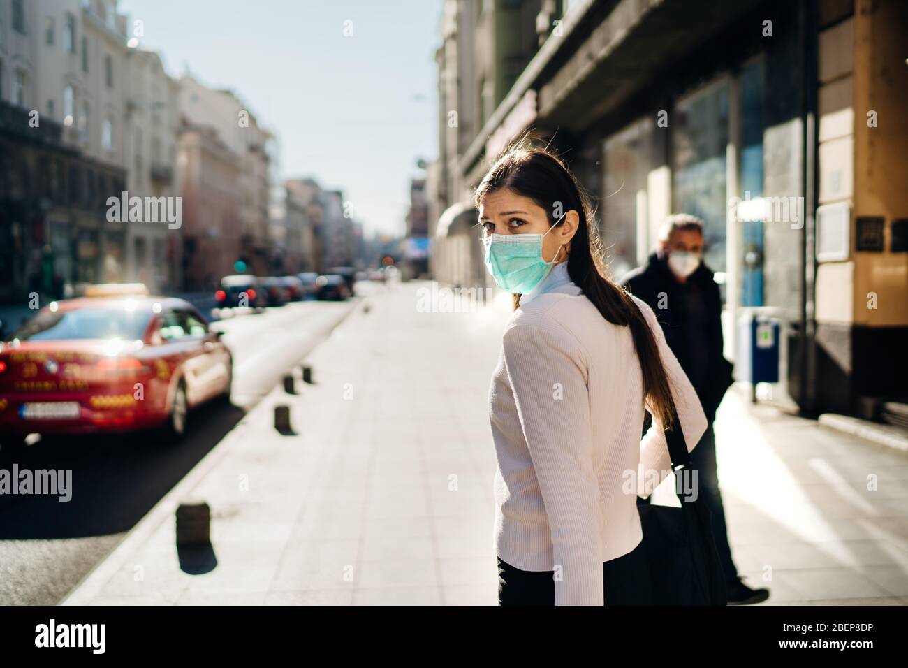 Anxious young adult affected by the COVID-19.Walking,going to work during pandemic.Protective measures,mask wearing.Respecting guidelines.Avoiding con Stock Photo