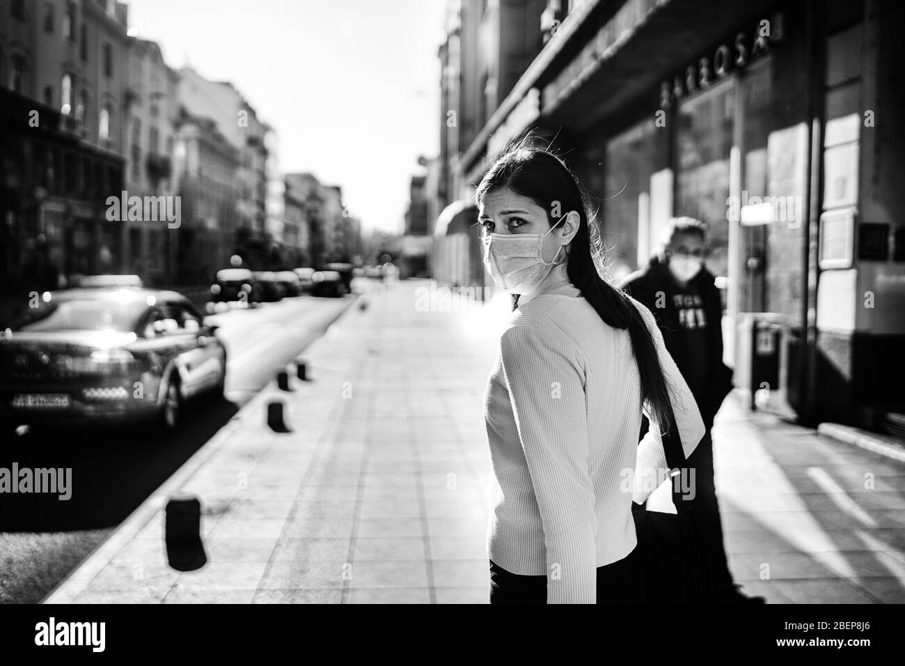 Anxious young adult affected by the COVID-19.Walking,going to work during pandemic.Protective measures,mask wearing.Respecting guidelines.Avoiding con Stock Photo