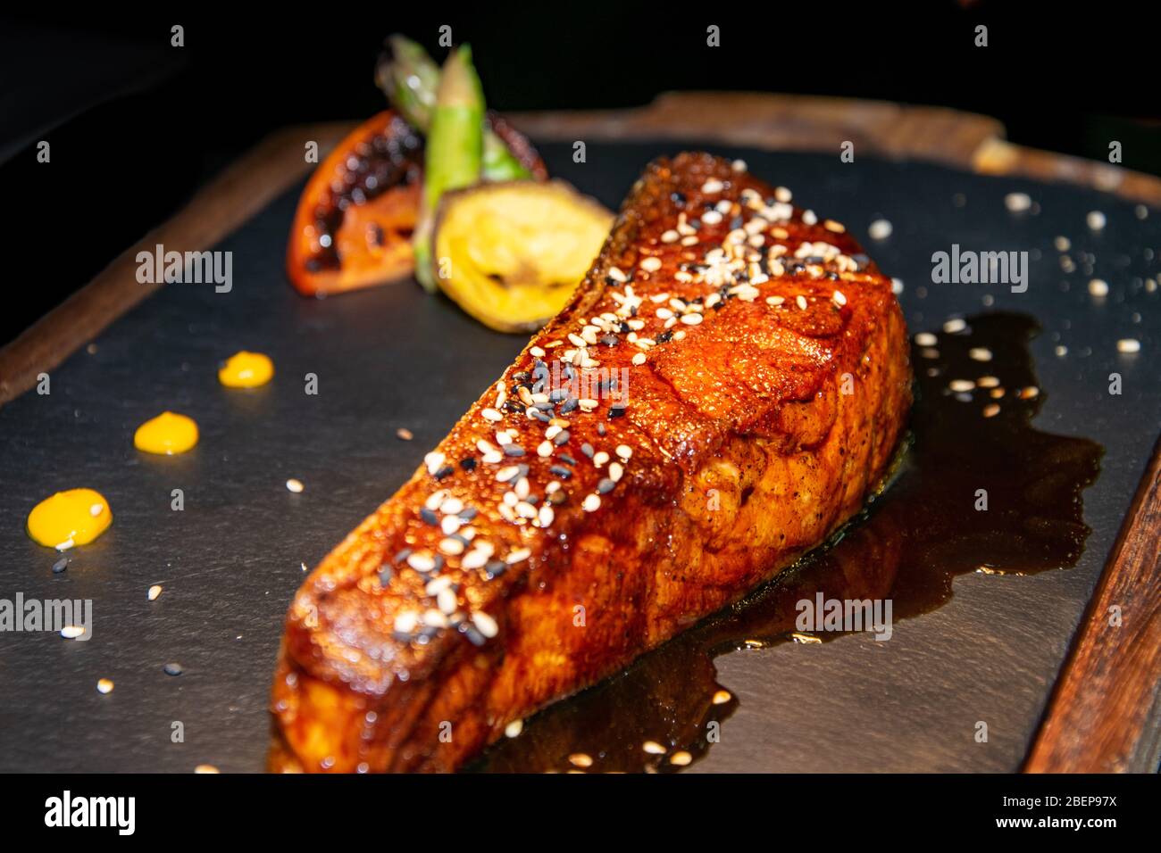 a piece of Canadian salmon cooked in a teriyaki sauce served on a stone and wood plate Stock Photo