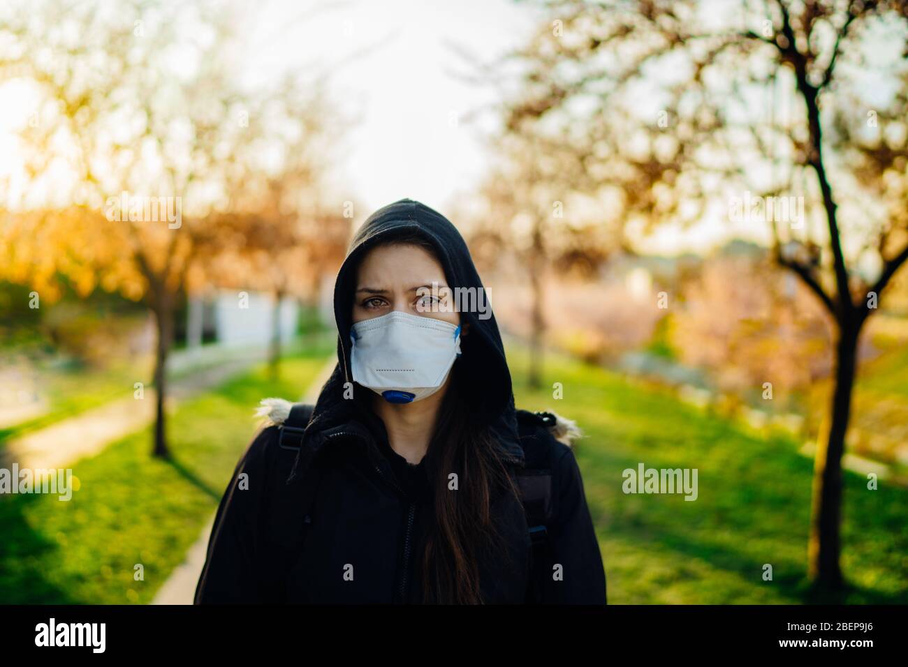 Depressed scared person wearing a N95 mask to prevent contracting disease in spring nature.Coronavirus pandemic life.Infection panic and fear.Emotiona Stock Photo