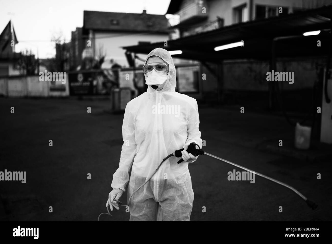 Sanitation service worker spraying disinfectant with a spray gun in hazmat suit,N95 mask and protective gear.Private protective equipment (PPE).Quaran Stock Photo