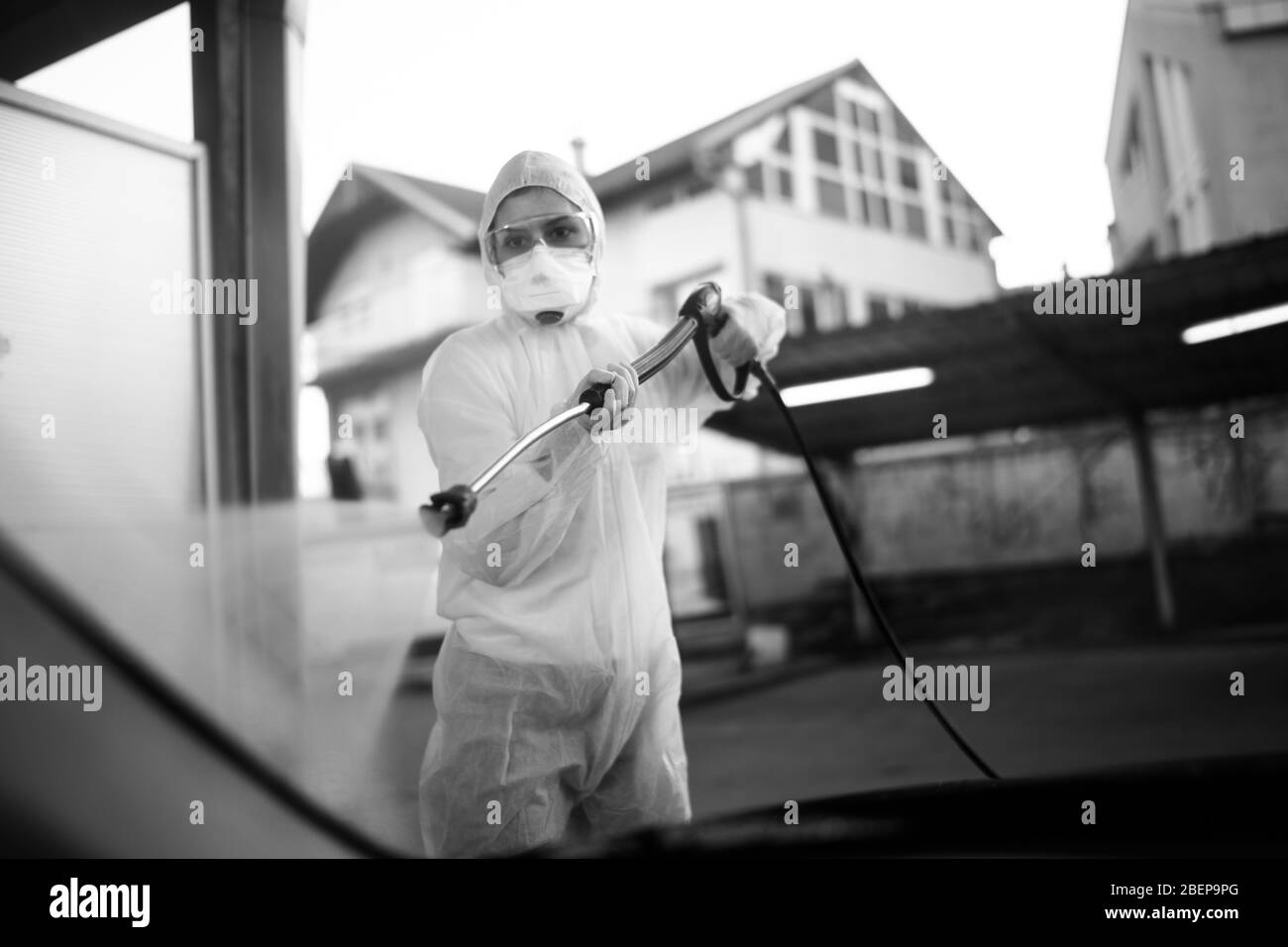 Sanitation service worker spraying disinfectant with a spray gun in hazmat suit,N95 mask and protective gear.Private protective equipment (PPE).Quaran Stock Photo