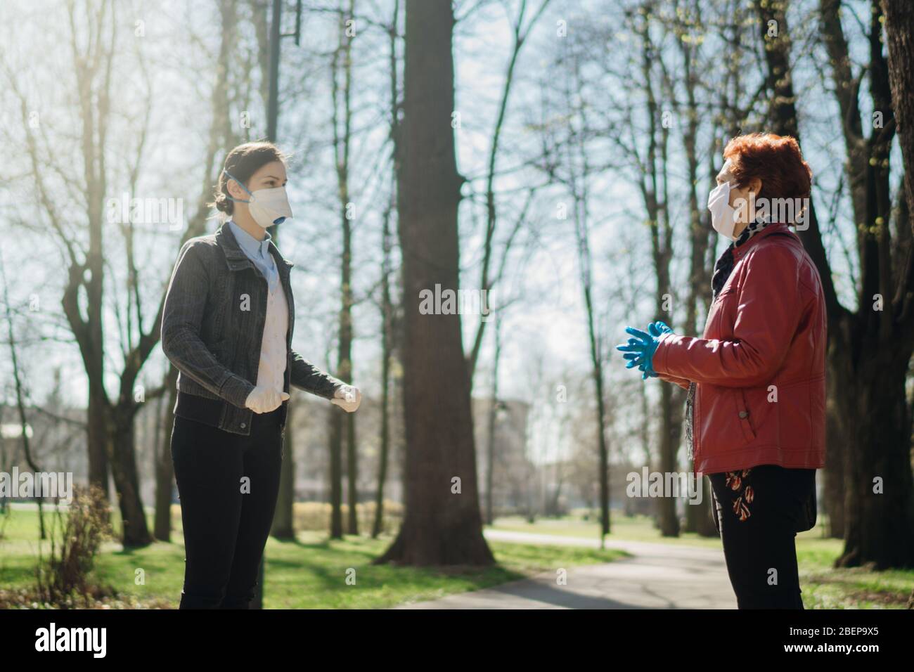 Elderly woman with protective face mask/gloves talking with a friend.Coronavirus COVID-19 disease protection.Conversation from a safe distance.Sociali Stock Photo