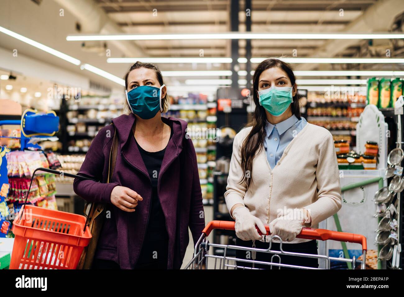 Shoppers with masks buying for groceries due to coronavirus pandemic in grocery store.COVID-19 food shopping.Quarantine preparation.Panic buying and s Stock Photo
