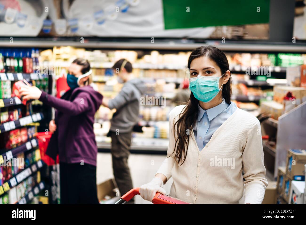Shopper with mask safely buying for groceries due to coronavirus pandemic in grocery store.COVID-19 shopping.Quarantine preparation.Panic buying and s Stock Photo