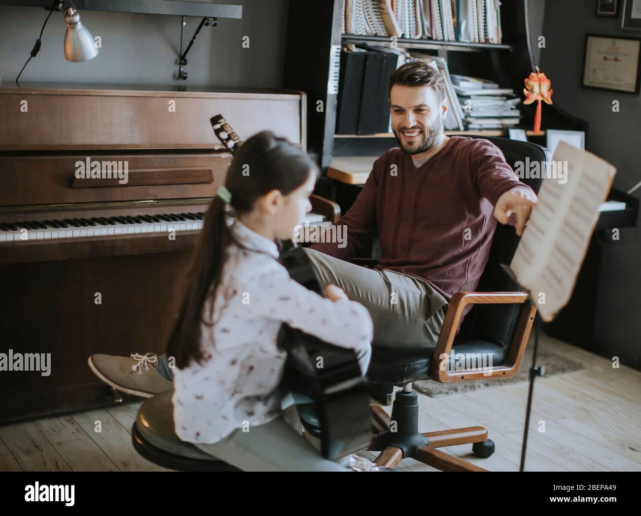 Cute little girl playing guitar with her music teacher in the rustic
