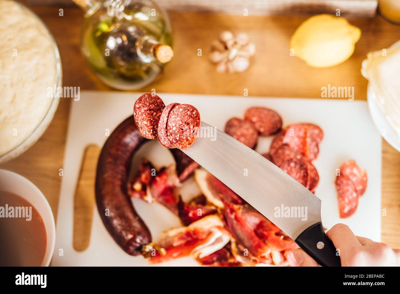 Homemade dry cured smoked spicy sausage.Delicatessen meats. Charcuterie board assembly.Meat/protein snack.Pepperoni pizza topping.Thin slices of sausa Stock Photo