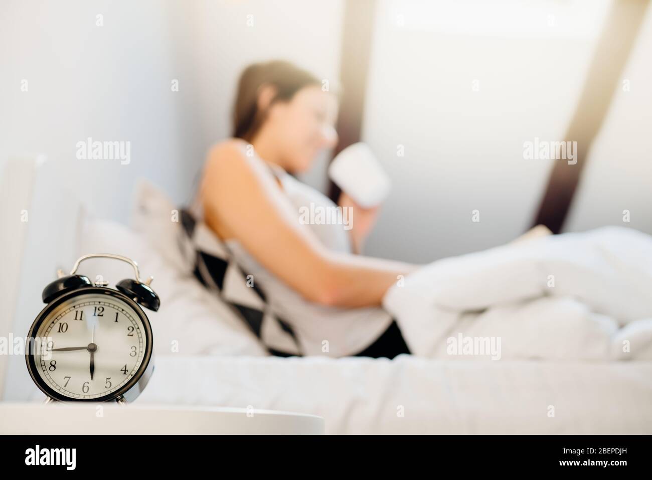 Alarm clock ringing.Woman waking up in early morning for work.Obstructive sleep apnea effects.Mental stress sleep depression.Melatonin deficiency.Narc Stock Photo
