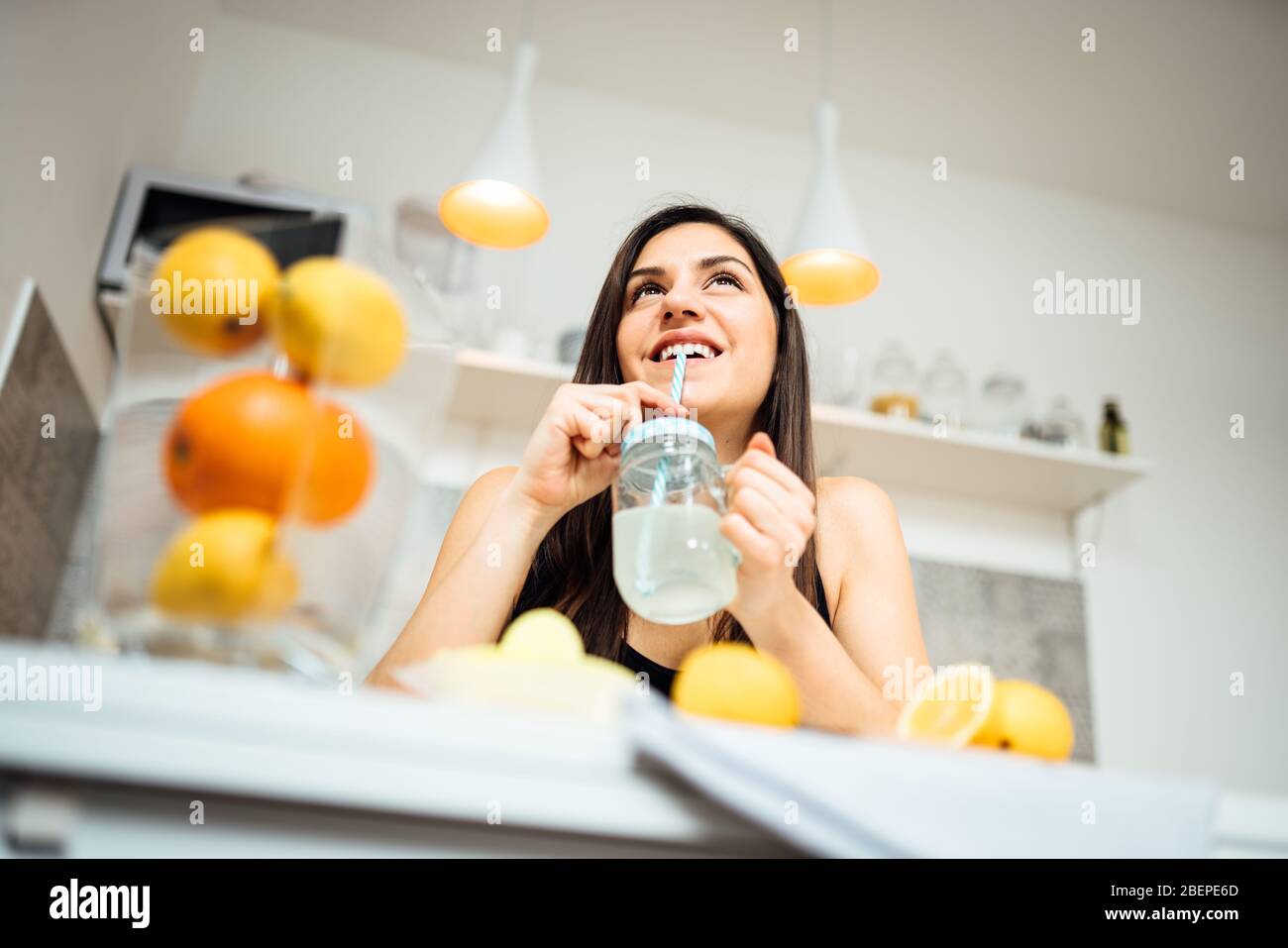 Healthy cheerful woman drinking homemade organic mixed citrus fruit drink.Making lemonade.Detox diet,nutrition.Food for oily skin,strong immune system Stock Photo