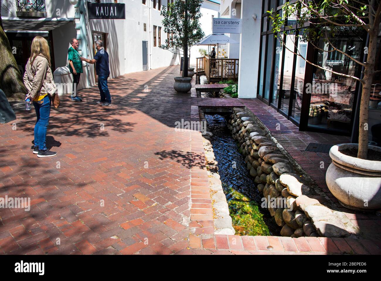 Clean water flows in historic channels on the pavement in Stellenbosch. The water furrows were designed hundreds of years ago to provide water for gardens and houses. There is a ready supply of fresh water in the area and it has helped the town to flourish. Stock Photo