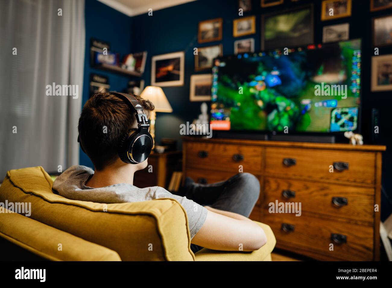 Adult gamer with headphones playing internet MMORPG cyber strategy online video game on computer gaming rig.Abstract virtual reality world.Spending ti Stock Photo