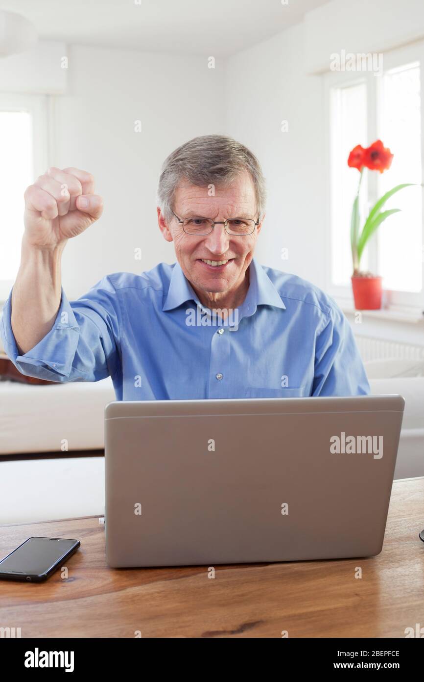 Joyful mature businessman working at home office in a bright living room - focus on the face Stock Photo