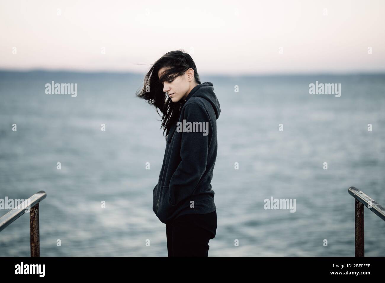 Stressed sad woman in bad mood overthinking problems,looking at the sea/ocean.Person being alone.Social distancing loneliness.Emotional challenge and Stock Photo