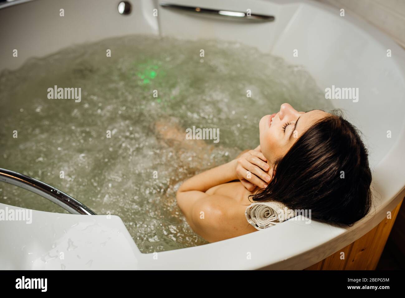Woman relaxing at home in the hot tub bath ritual.Spa day moment in modern bathroom indoors jacuzzi tub.Leisure activity.Self care.Good personal hygie Stock Photo