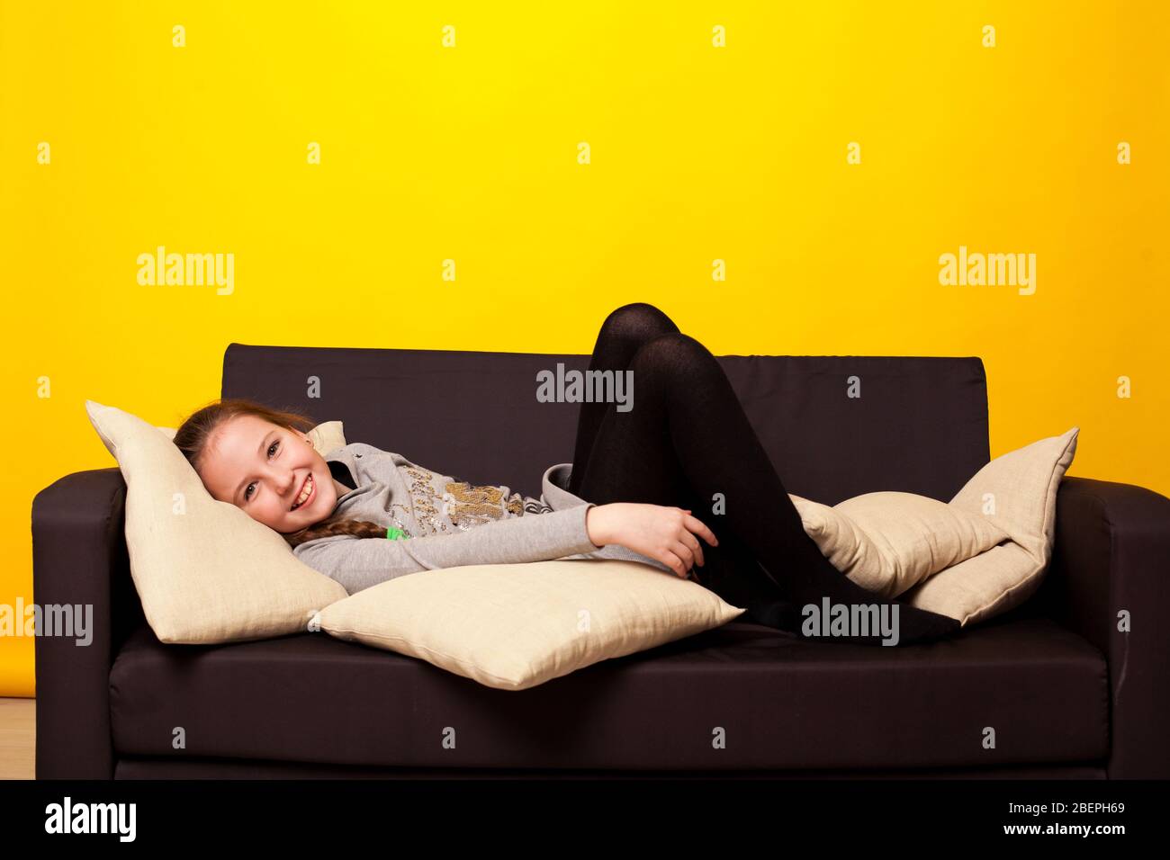 Beautiful little girl lies in a room on the couch Stock Photo - Alamy
