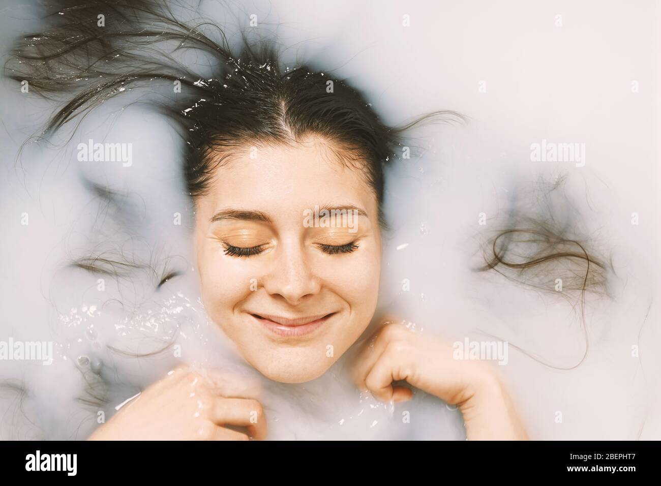young woman taking a bath in milk - happy with closed eyes - self care and wellbeing concept Stock Photo