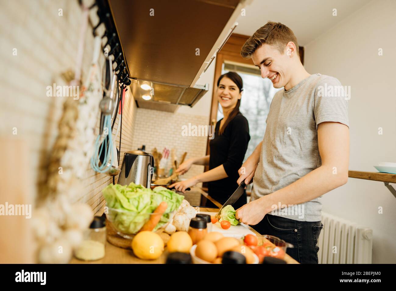 Happy couple enjoying cooking time together at home.Enjoying simple moments.Making vegan dishes.Having fun while making food,bonding.Man helping in th Stock Photo