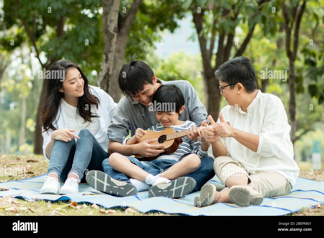 Happy family with grandma, mom with dad teaching son playing guitar and  sing a song in park, Enjoy and relax people picnic outside Stock Photo -  Alamy