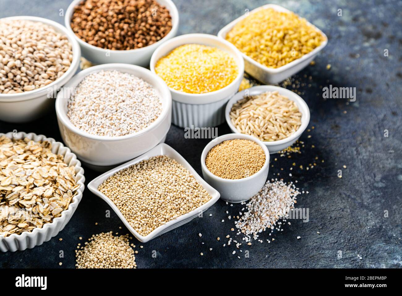 Selection of whole grains in white bowls rice, oats, buckwheat