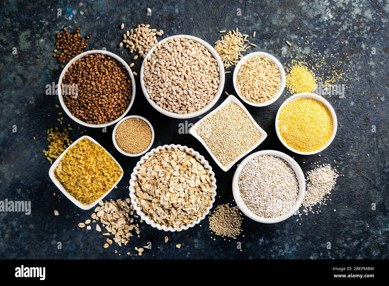 Selection of whole grains in white bowls rice, oats, buckwheat