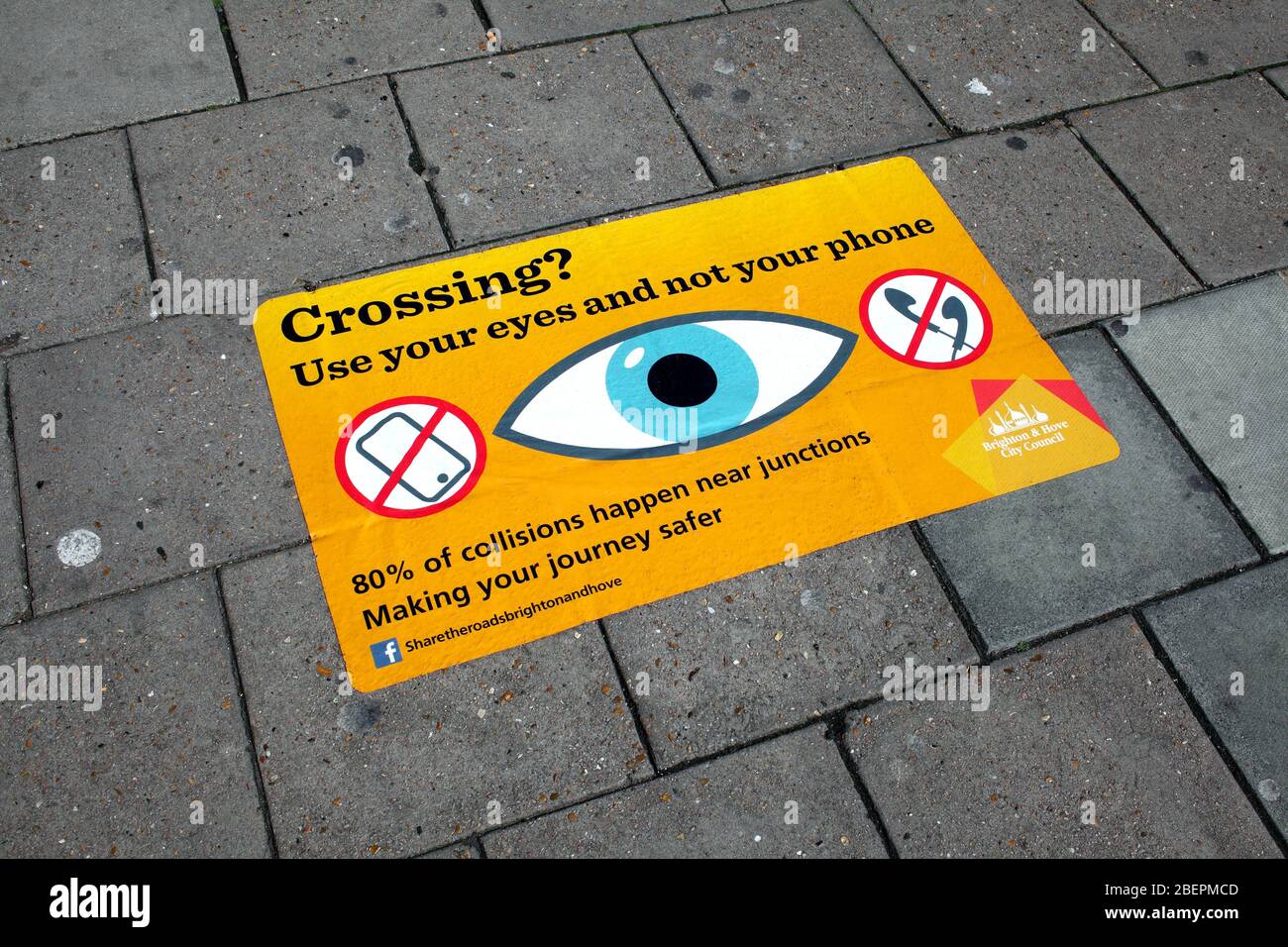 Warning sign, on a pavement, positioned to be seen by people who look down at their phones instead of looking where they are going. Stock Photo