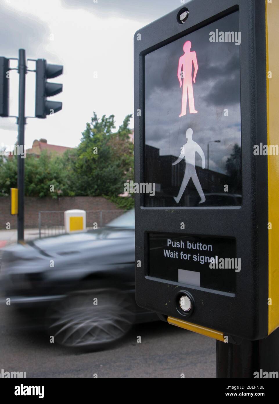 Red man on pedestrian crossing sign as a car passes through traffic lights. Stock Photo