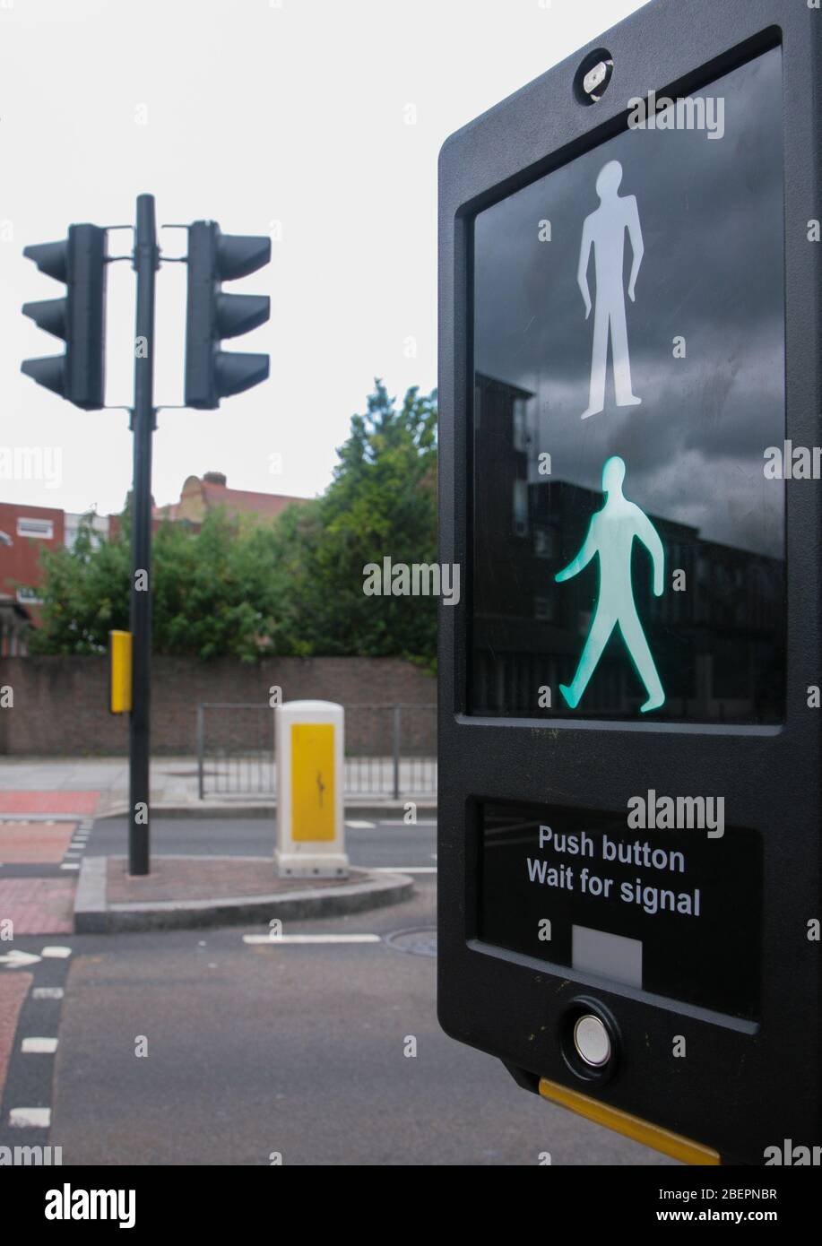 Green man on pedestrian Crossing sign at traffic lights on the roadside. Stock Photo