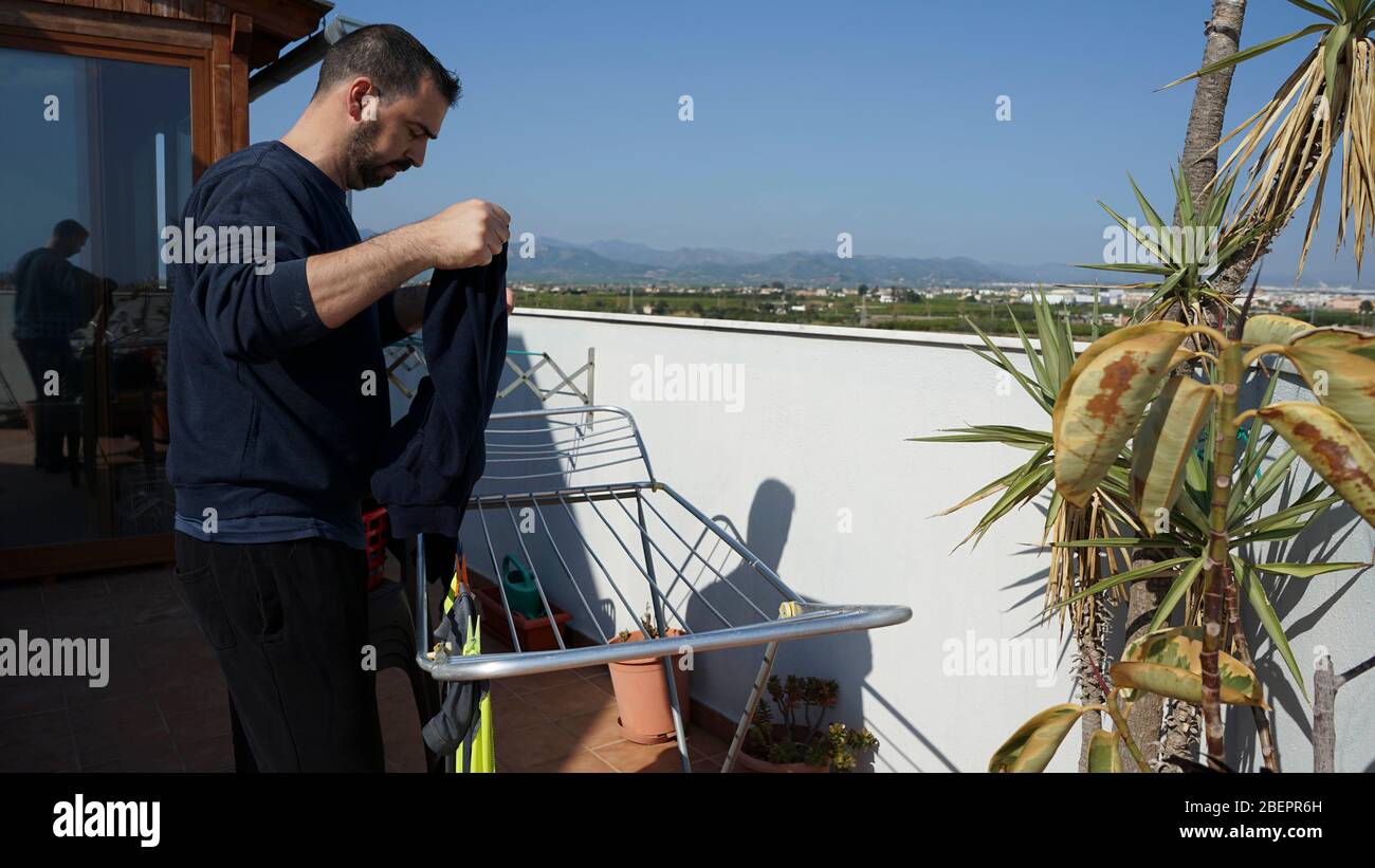Man hanging clothes on the terrace of his house Stock Photo