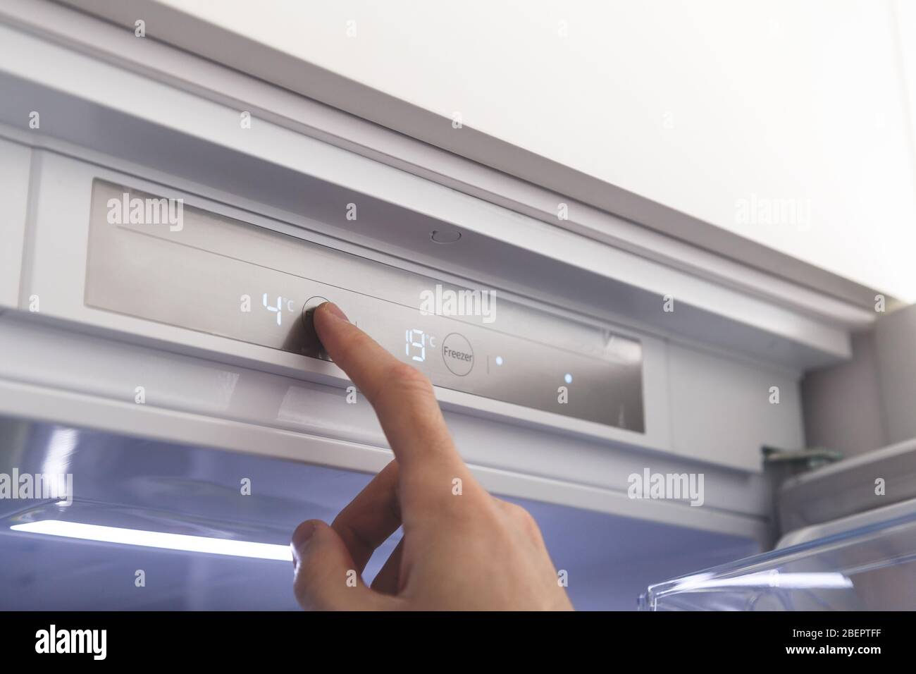 Hand sets temperature of refrigerator Stock Photo