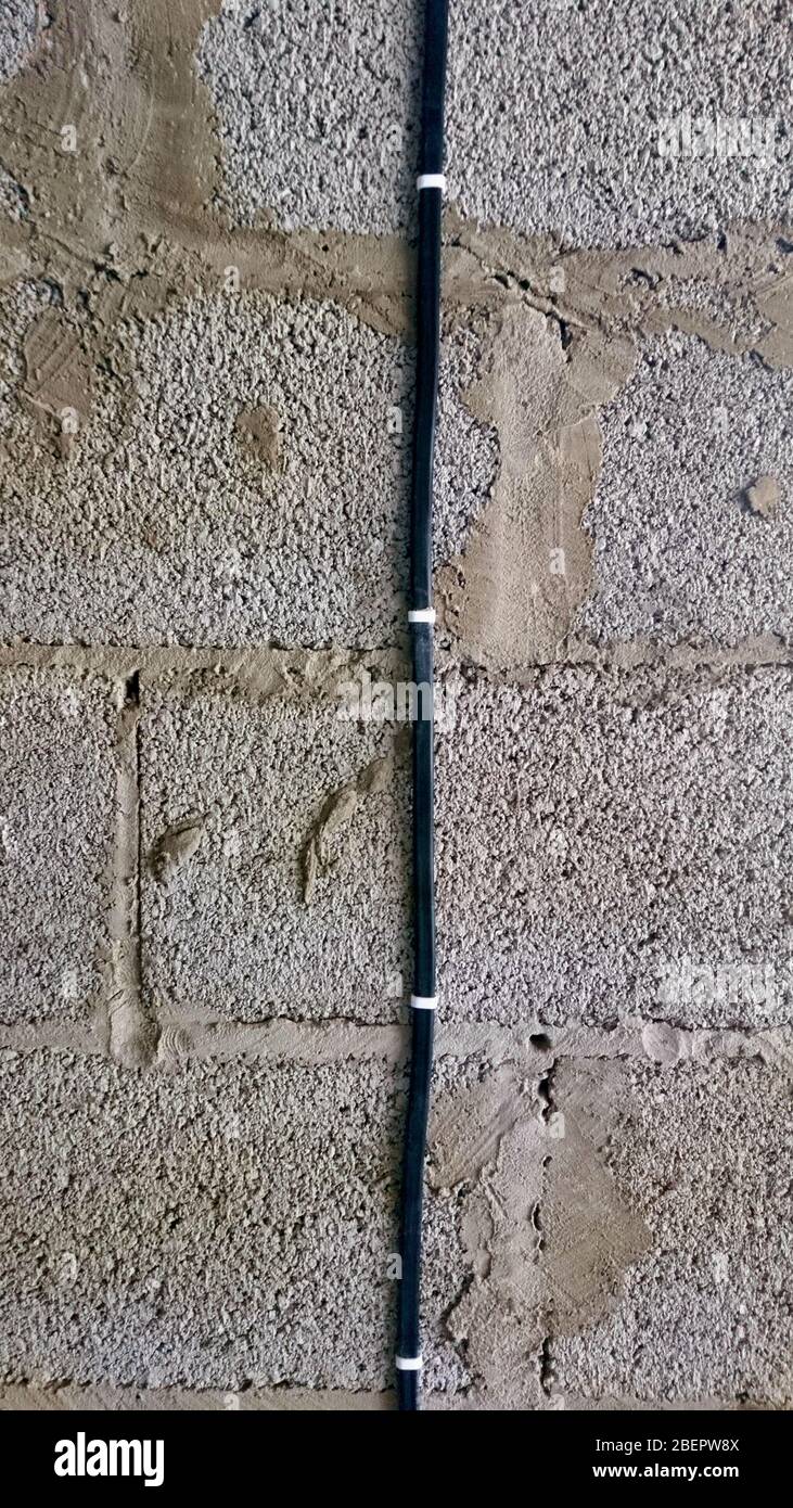 flat cable secured with clamps on the cinder block wall Stock Photo