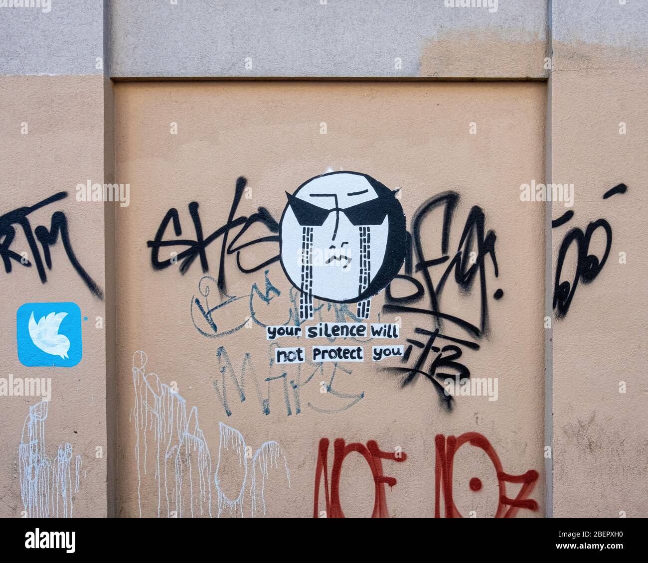 Graffiti, little white painted bird and 'your silence will not protect you'  with paste-up of crying face Stock Photo