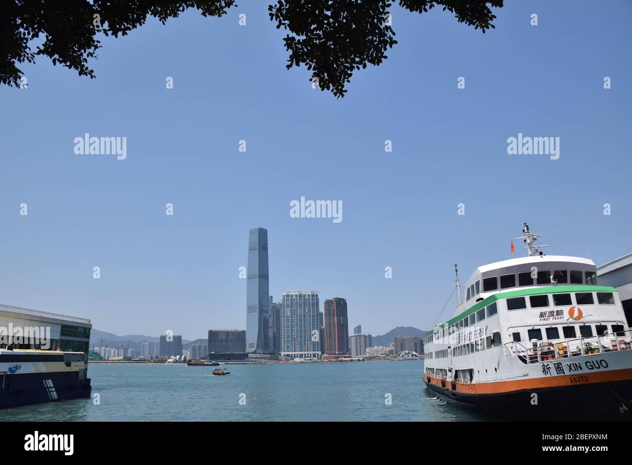 A ferry in the sea and the International Commerce Centre (also called ICC) from Central ferry pier - Hong Kong Stock Photo