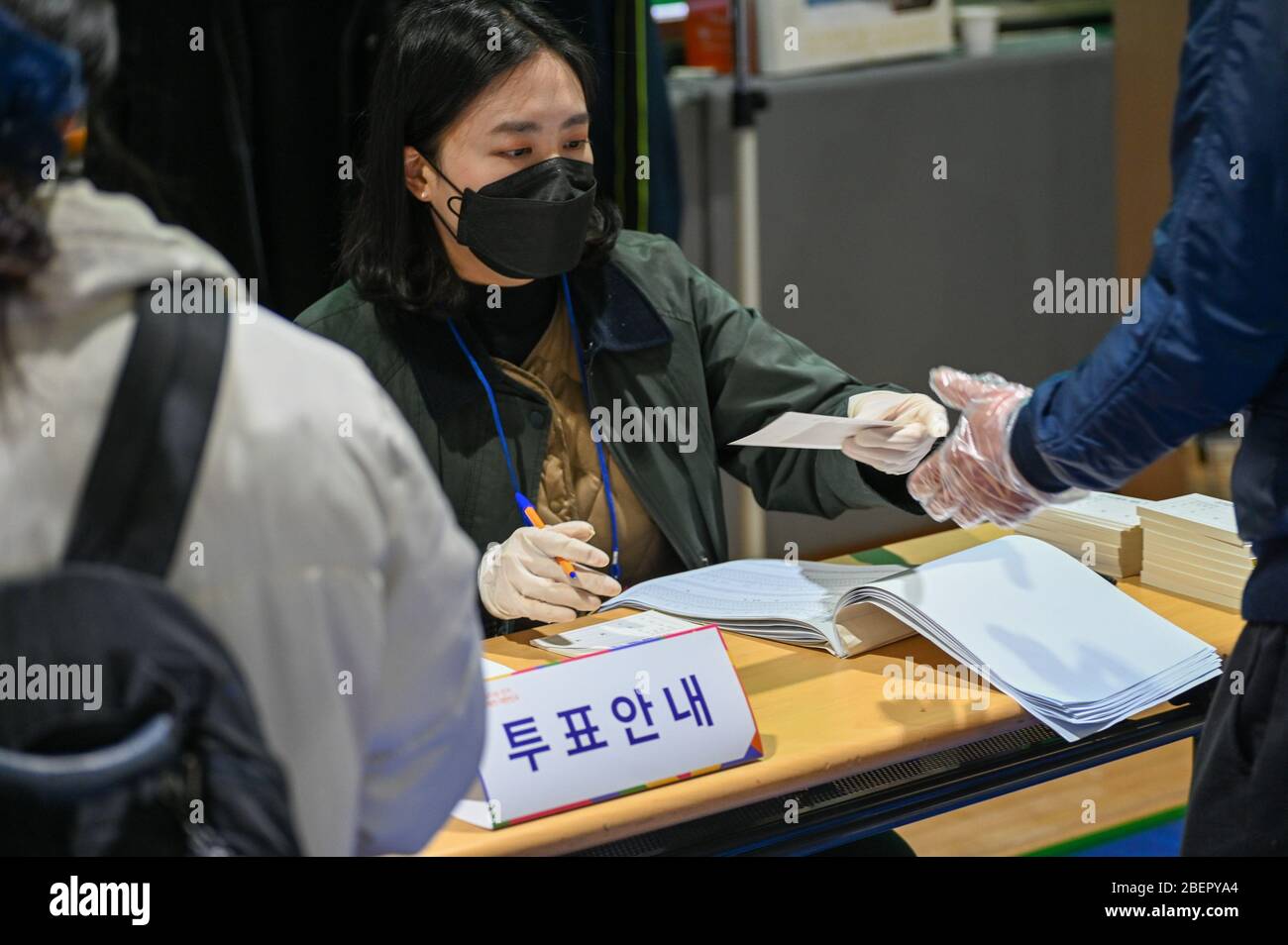 Seoul, South Korea. 15th Apr, 2020. A poll worker in Seoul checks identification and hands a ballot to a voter in South Korea's parliamentary elections on Wednesday, April 15, 2020. Voters are to elect the country's 300-member National Assembly as South Korea and the world battles the coronavirus COVID-19. Photo by Thomas Maresca/UPI Credit: UPI/Alamy Live News Stock Photo