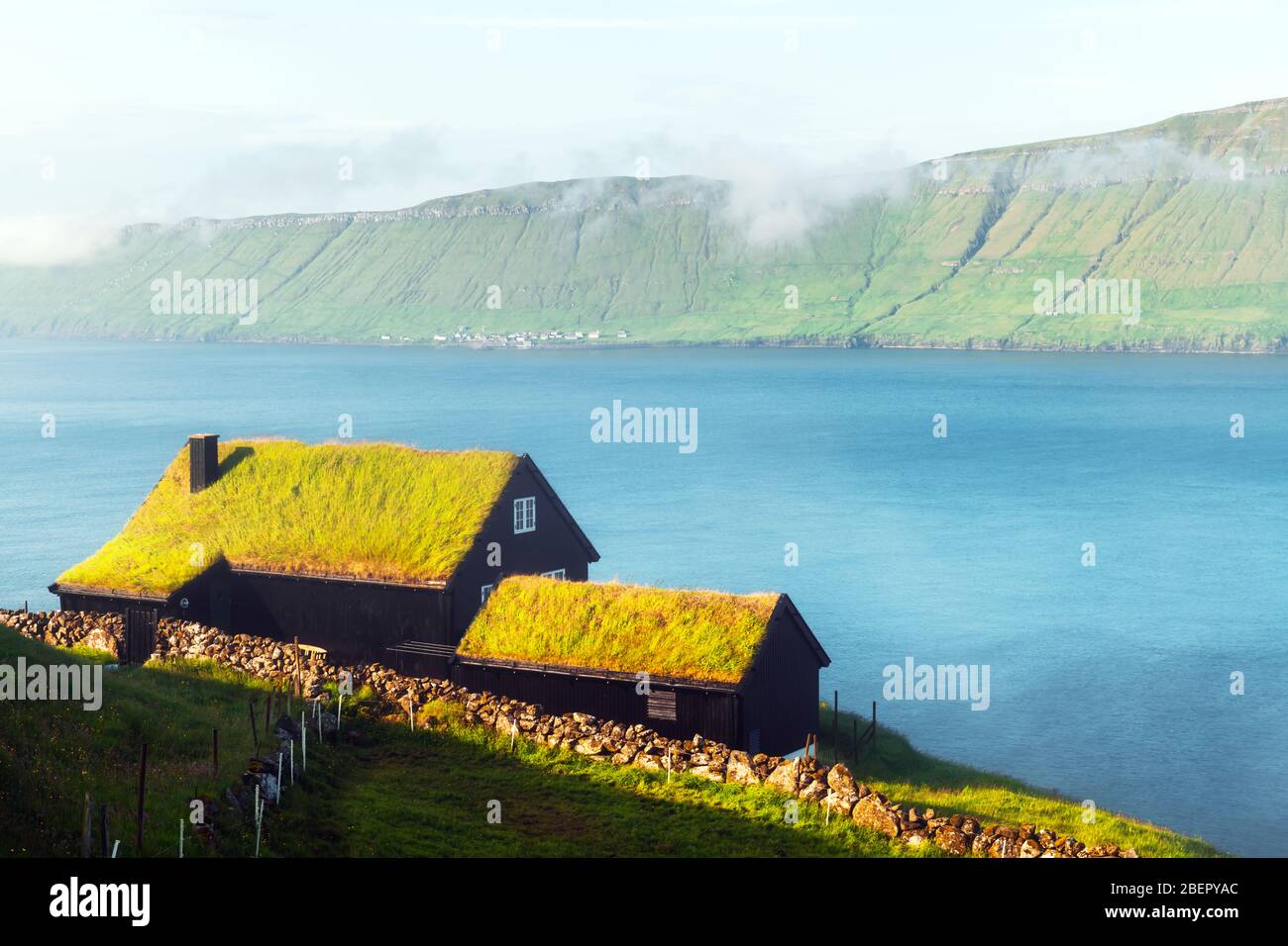 Foggy morning view of a house with grass roof in the Velbastadur village on Streymoy island, Faroe islands, Denmark. Landscape photography Stock Photo