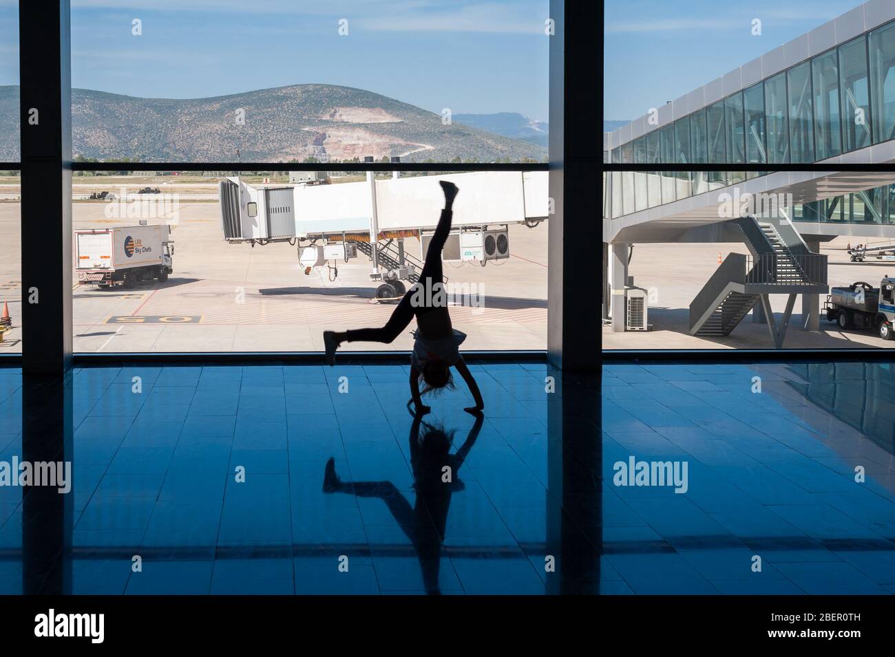 05/26/2019. Bodrum Airport / Milas Mugla Airport. Turkey. Small girl doing cartwheels exercise out of boredom while awaiting for her flight. Stock Photo