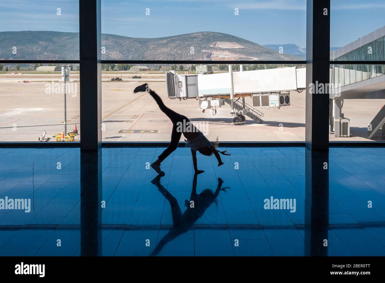 05/26/2019. Bodrum Airport / Milas Mugla Airport. Turkey. Small girl doing cartwheels exercise out of boredom while awaiting for her flight. Stock Photo