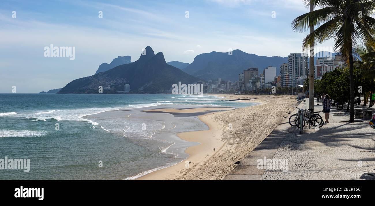 Almost empty Ipanema beach and boulevard with the Two Brothers mountain in the background during the COVID-19 outbreak in Rio de Janeiro Stock Photo