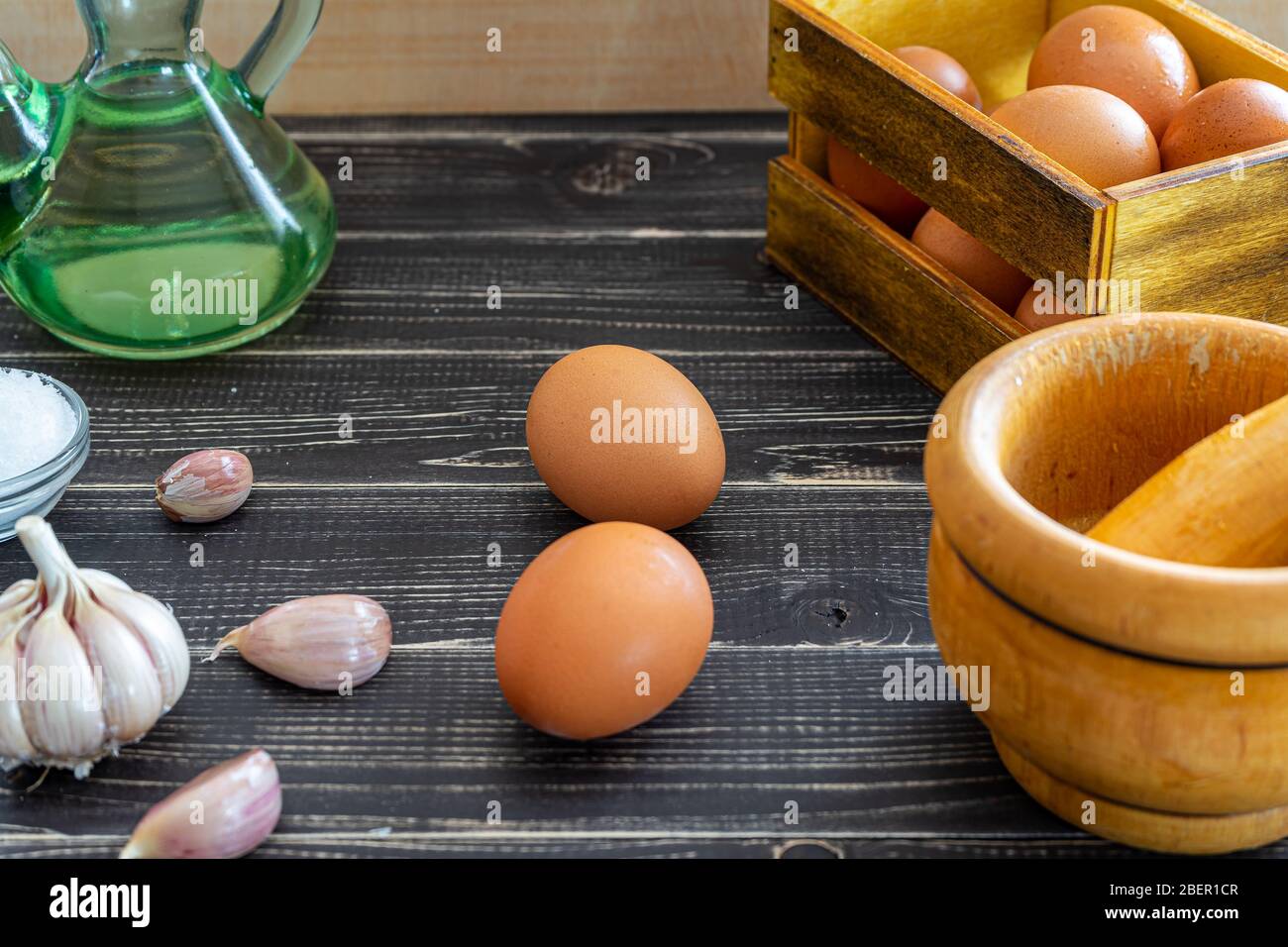 Garlic heads, eggs, salt, and oil distributed to prepare the ajoaceite sauce typical of Spanish food in a month ofworn and old black wood Stock Photo