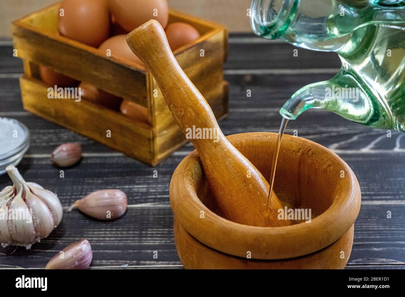 Garlic heads, eggs, salt, and oil distributed to prepare the ajoaceite sauce typical of Spanish food in a month ofworn and old black wood Stock Photo