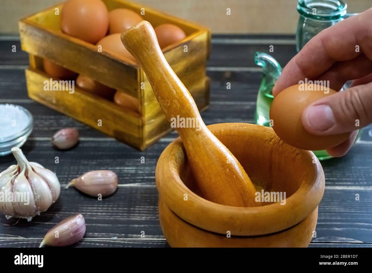 Garlic heads, eggs, salt, and oil distributed to prepare the ajoaceite sauce typical of Spanish food in a month ofworn and old black wood Stock Photo