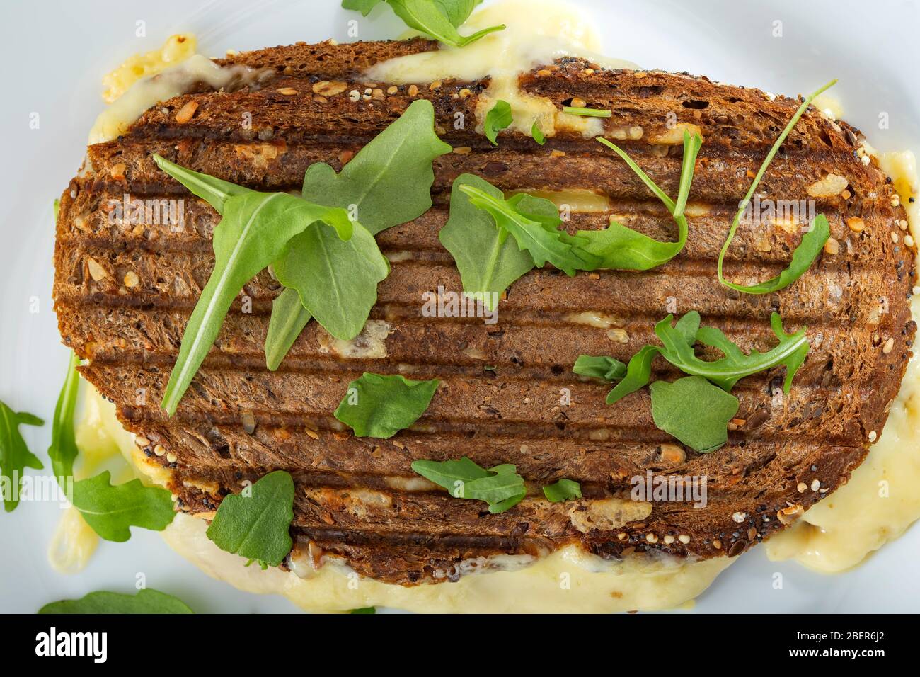 Toasted sandwich with a lot of cheese, ham and green arugula - top view Stock Photo