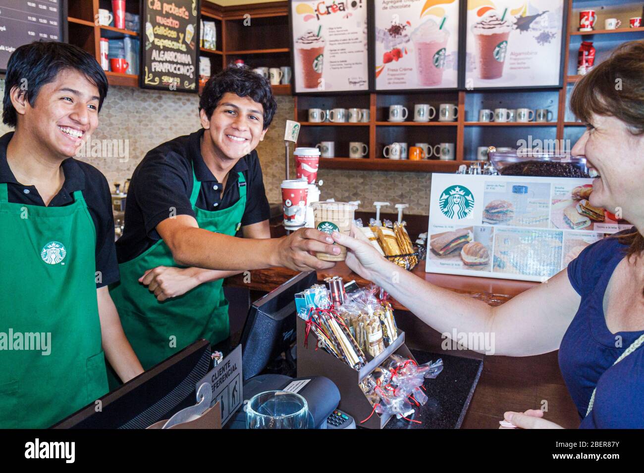 Lima Peru,Starbucks Coffee,inside interior barista baristas cafe,counter,serving green apron cashier,lattee cup,smiling Hispanic boys male teens woman Stock Photo