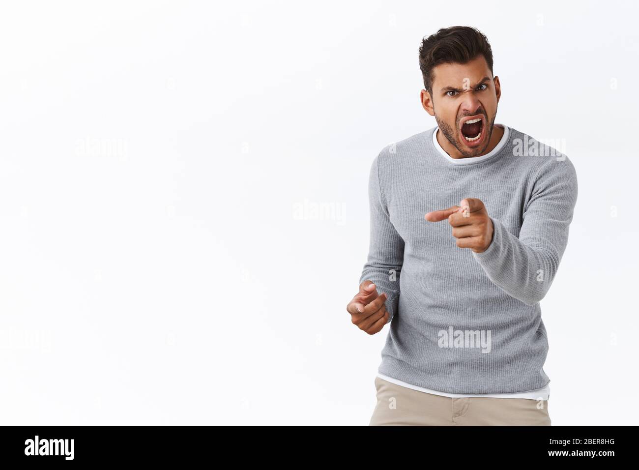 Outraged handsome man with bad temper losing control over emotions, distressed pointing camera and shouting accusations, blame someone in anger and Stock Photo